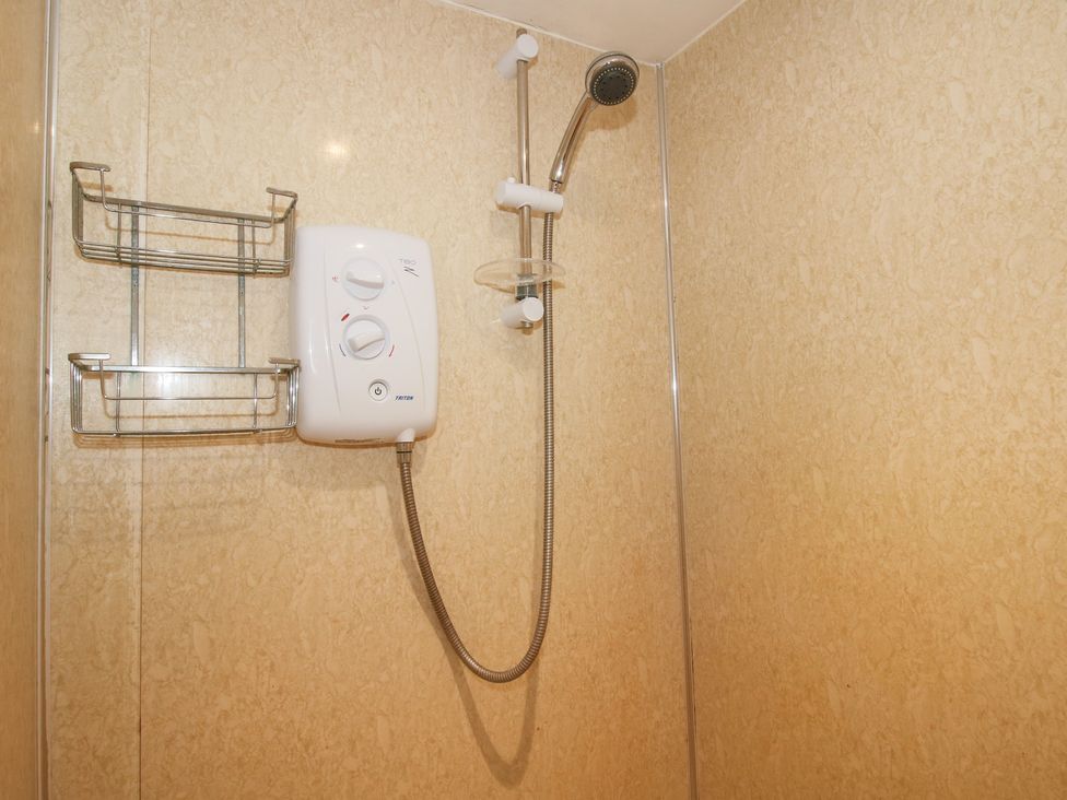 A shower with controls and storage at Millstone Cottages - Millstone Cottage in Westbury