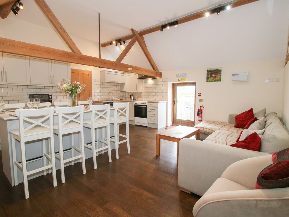 A kitchen with dining chairs and a sofa at Millstone Cottages - Breidden View, Westbury