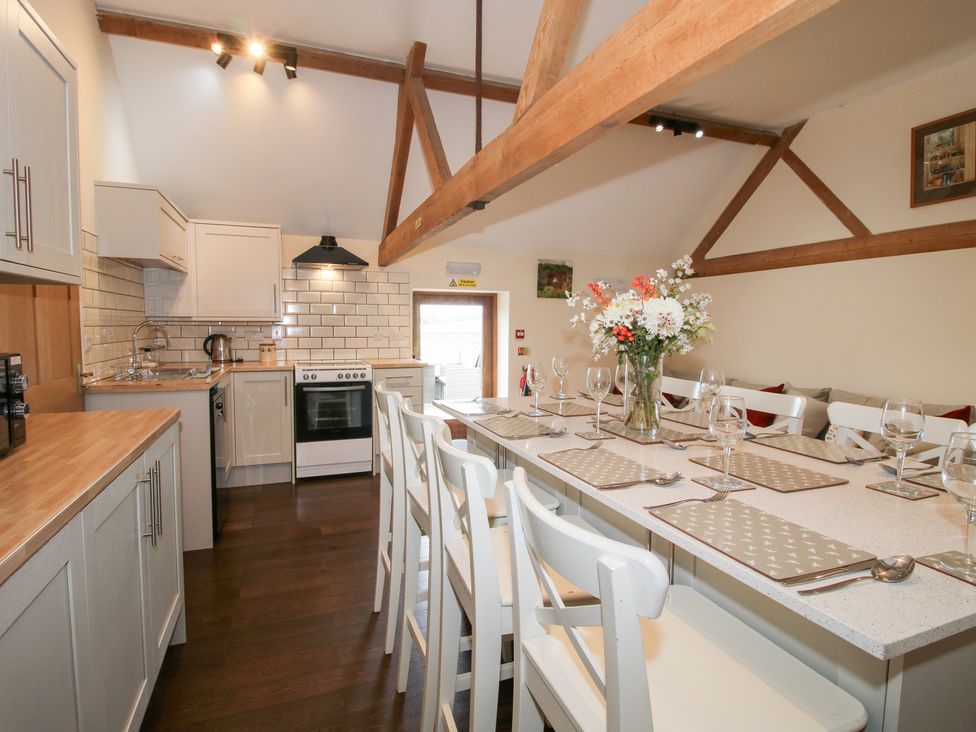 A kitchen with a bar counter and various appliances at Millstone Cottages - Breidden View Westbury