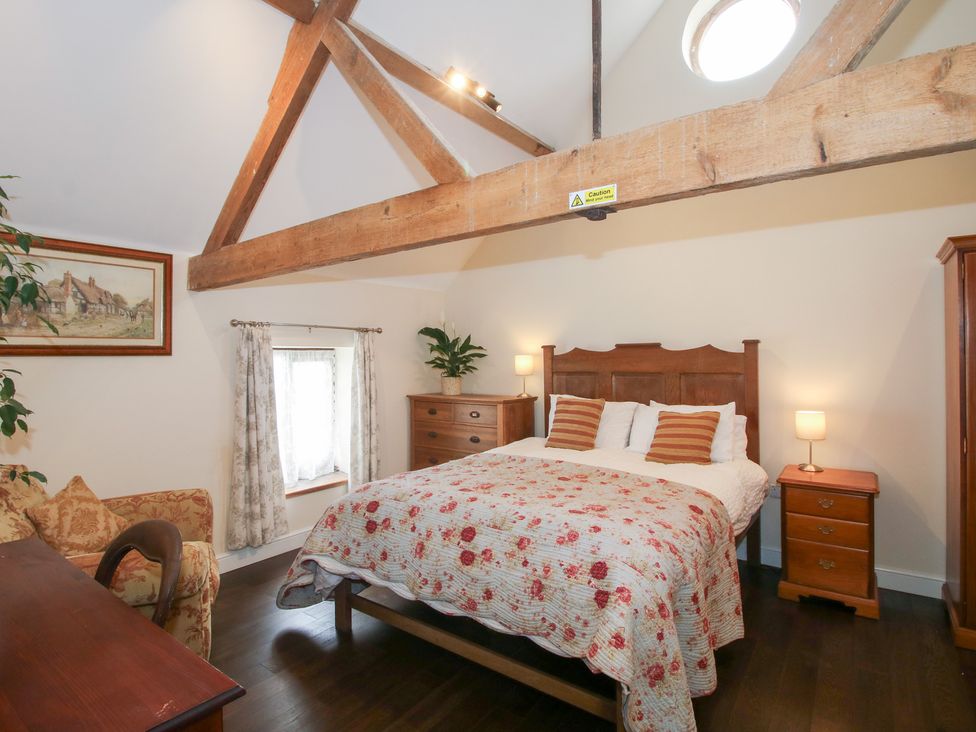 A bedroom with a bed, nightstand and chest of drawers at Millstone Cottages - Breidden View, Westbury