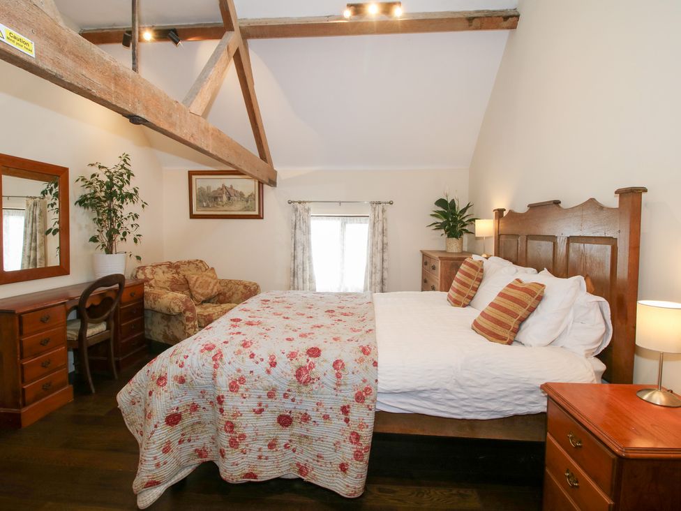 A bedroom with a bed, mirror, and sofa at Millstone Cottages - Breidden View, Westbury