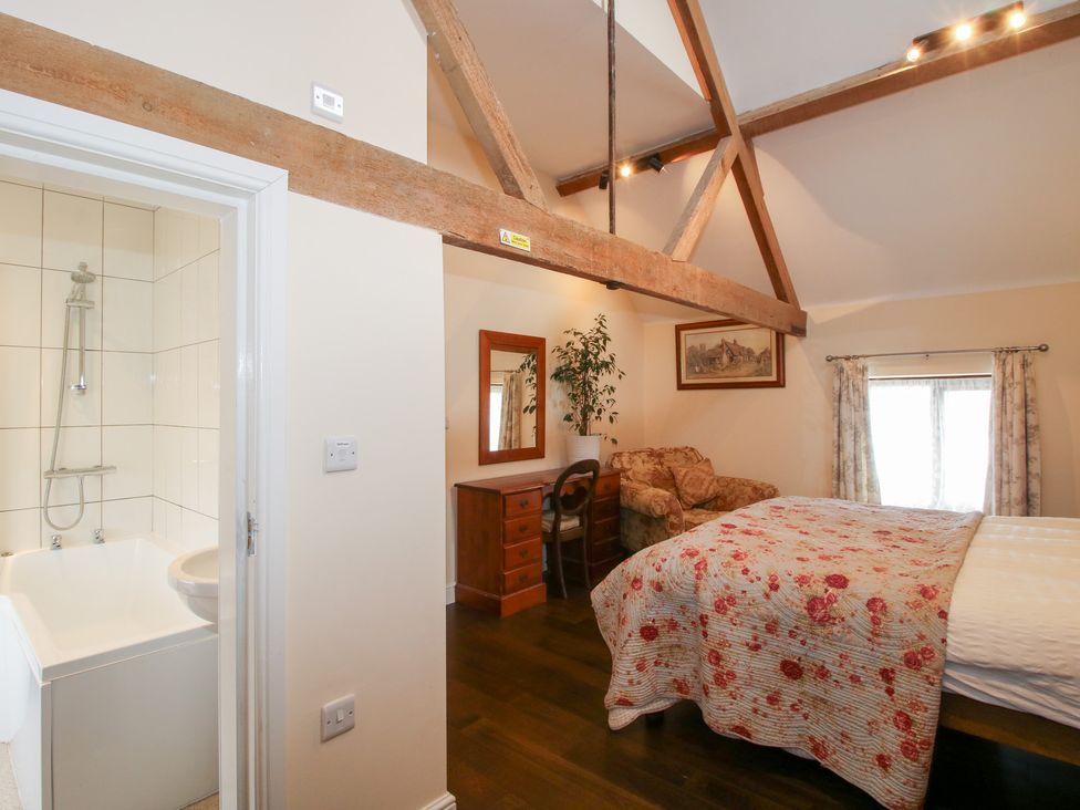 A bedroom with a bed and an adjoining bathroom at Millstone Cottages - Breidden View Westbury