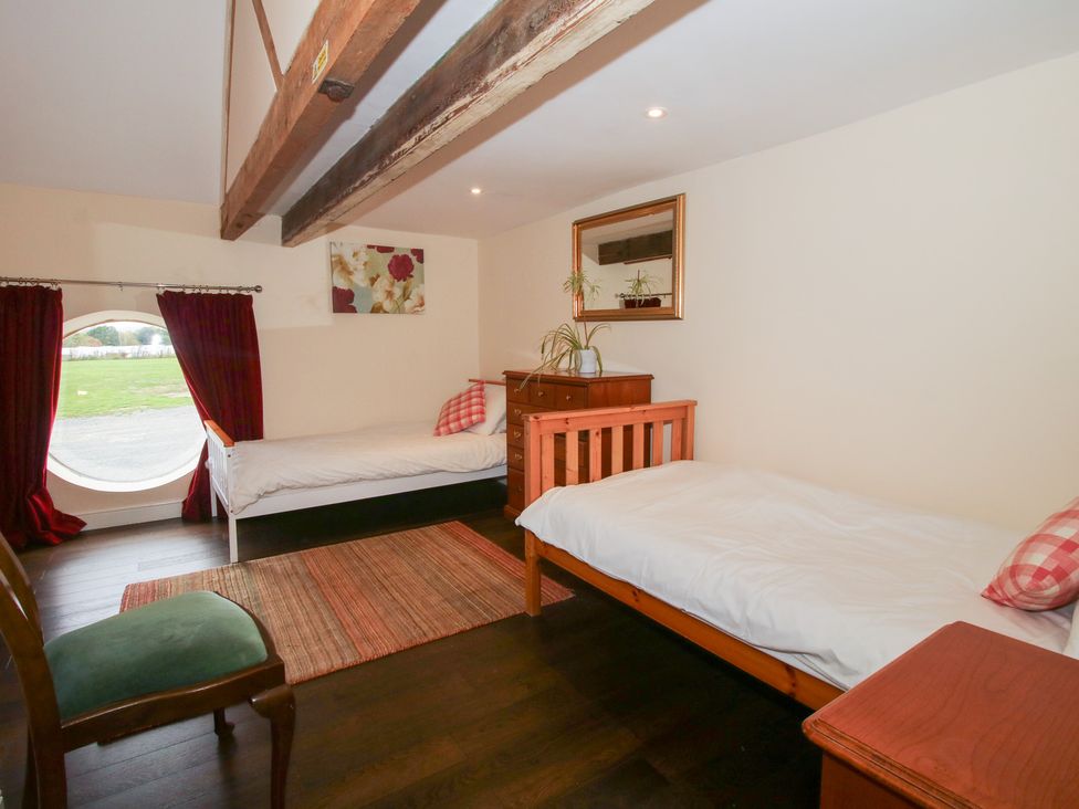 A bedroom with two beds and a table at Millstone Cottages - Breidden View, Westbury