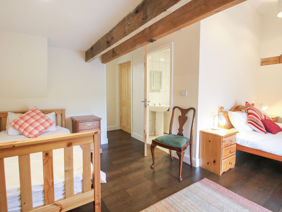 A bedroom with two beds and a chair at Millstone Cottages - Breidden View in Westbury
