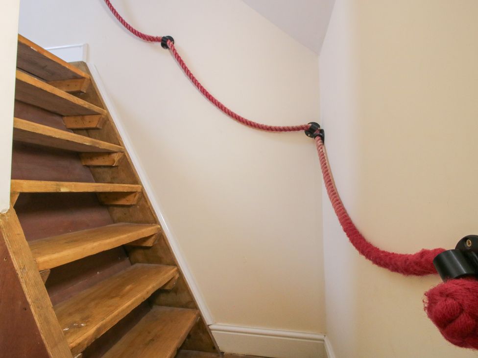 A staircase with wooden steps and a red rope handrail at Millstone Cottages - Breidden View, Westbury