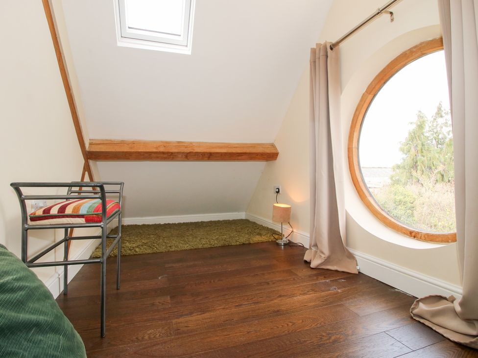 An attic space with a chair and lamp at Millstone Cottages - Breidden View in Westbury