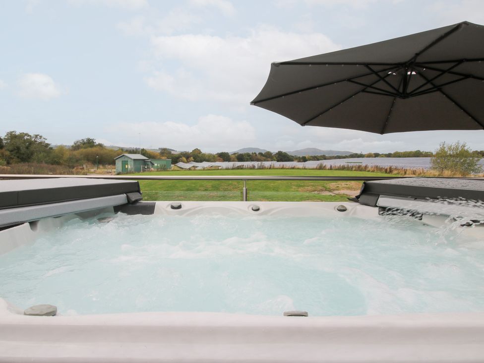 A hot tub with a view over a lake at Millstone Cottages - Breidden View in Westbury