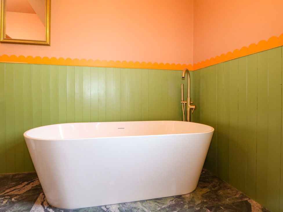 A bathroom with a bathtub and a mirror at Hasting Heights in Hastings