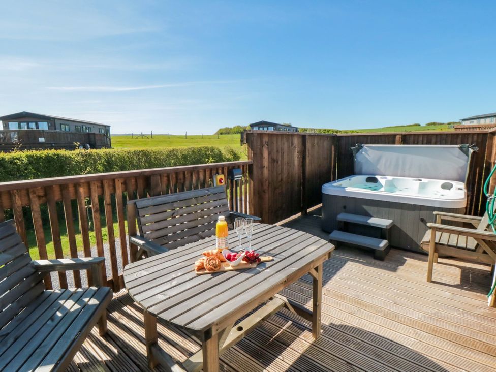 An outdoor seating area with a hot tub and a table set at Fir Lodge in Whitby