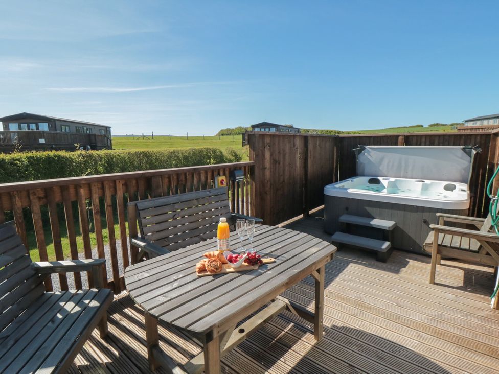 A deck with a hot tub and table setting at Fir Lodge in Whitby