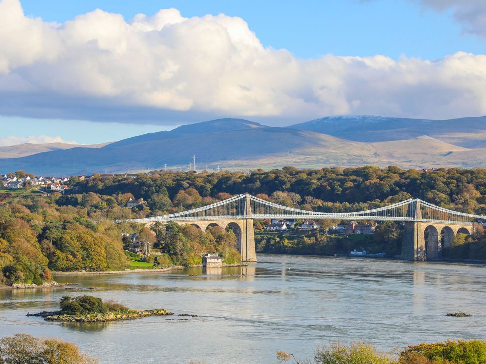 A bridge over a river surrounded by mountains and trees at Gorse Hill in Rhosneigr