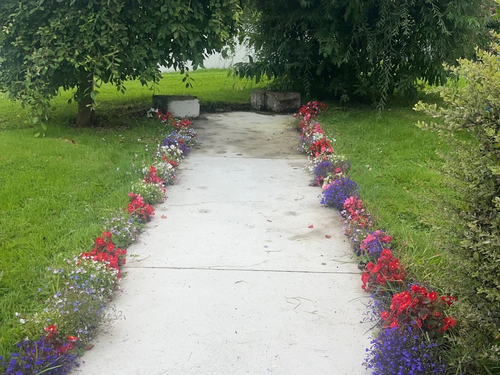 A pathway bordered by flowers and grass at Dromclough Farmhouse in Dromclough near Listowel, County Kerry