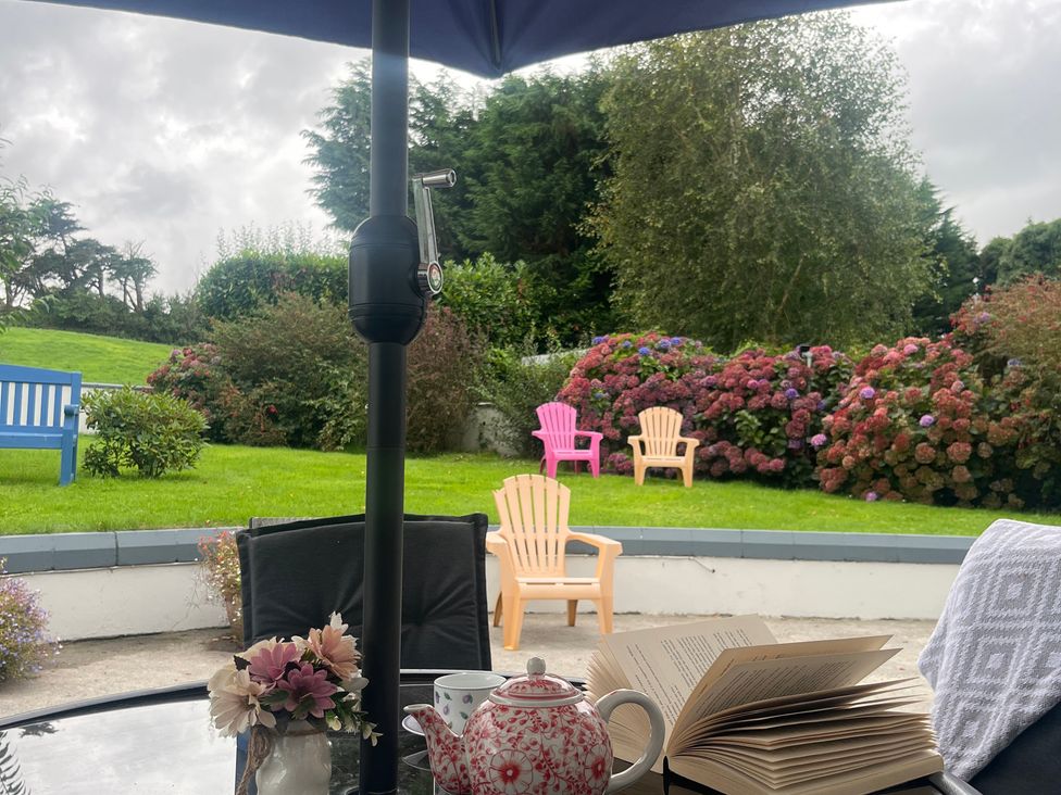 An outdoor seating area with a teapot and book on a table at Dromclough Farmhouse in Dromclough near Listowel, County Kerry