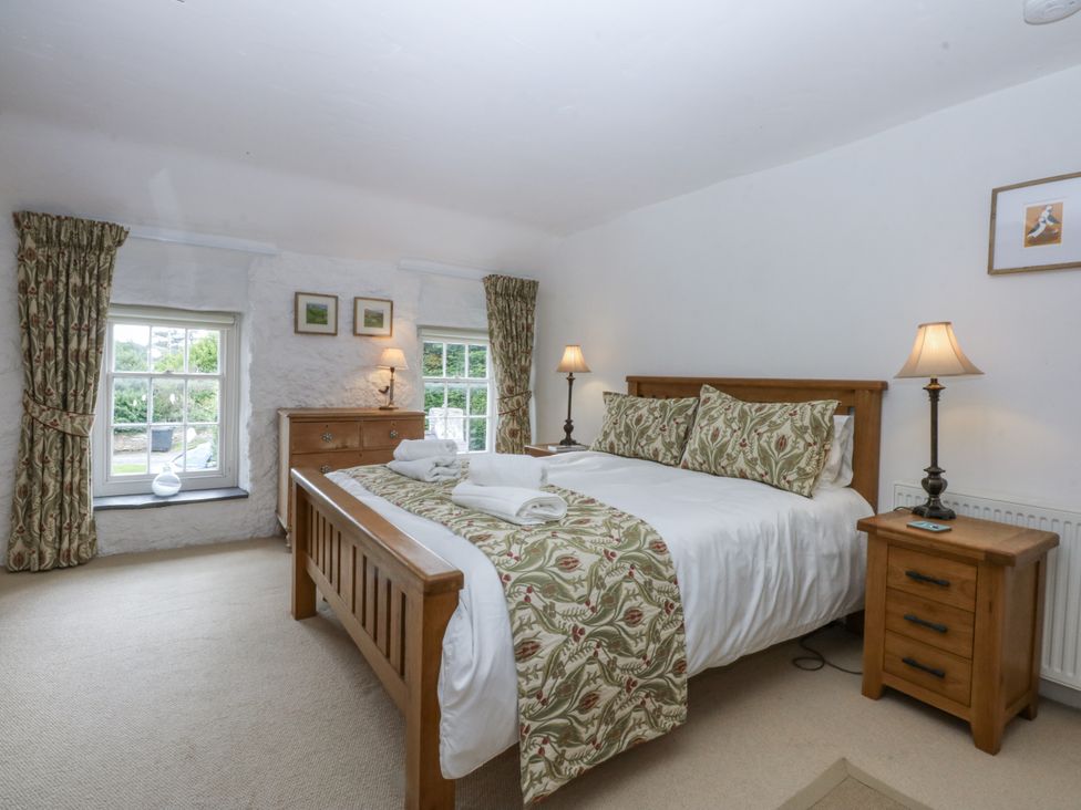 A bedroom with a double bed and two windows at Tyddyn Iolyn in Benllech
