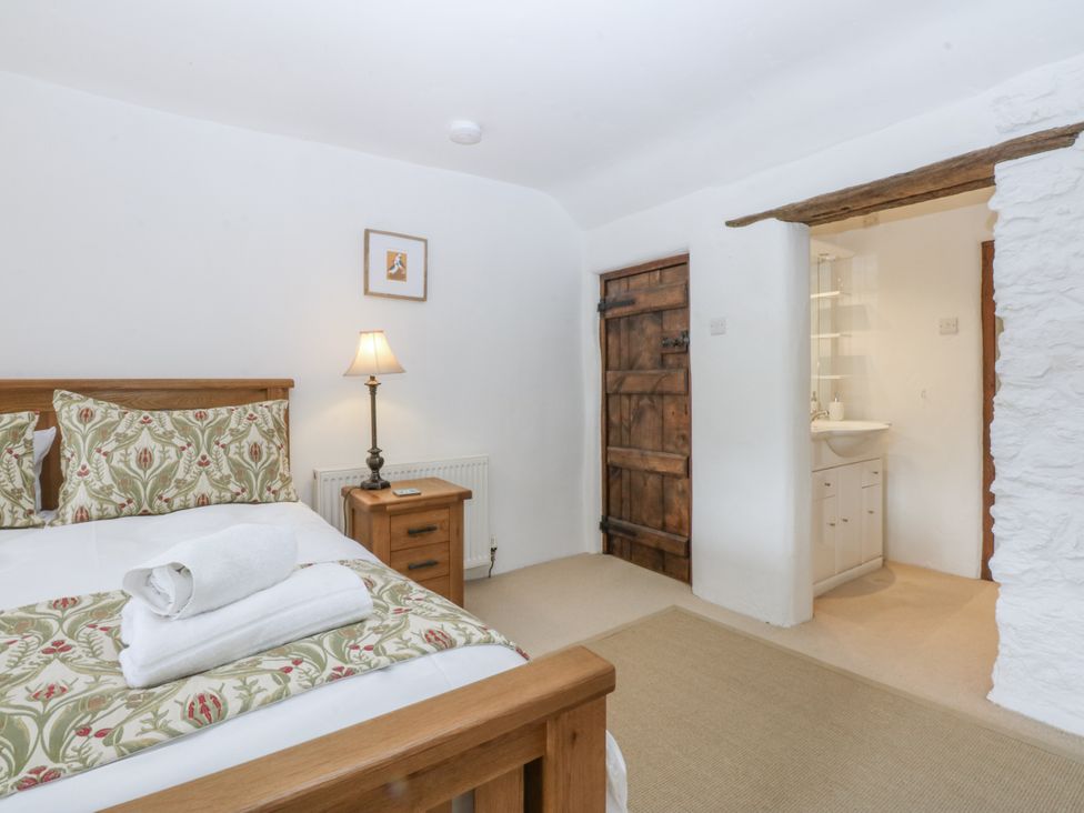 A bedroom with a wooden bed and attached washroom at Tyddyn Iolyn in Benllech
