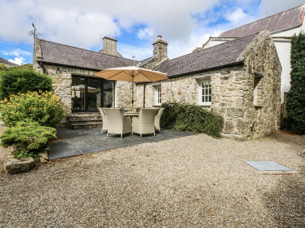 A stone building with an outdoor seating area at Tyddyn Iolyn Benllech