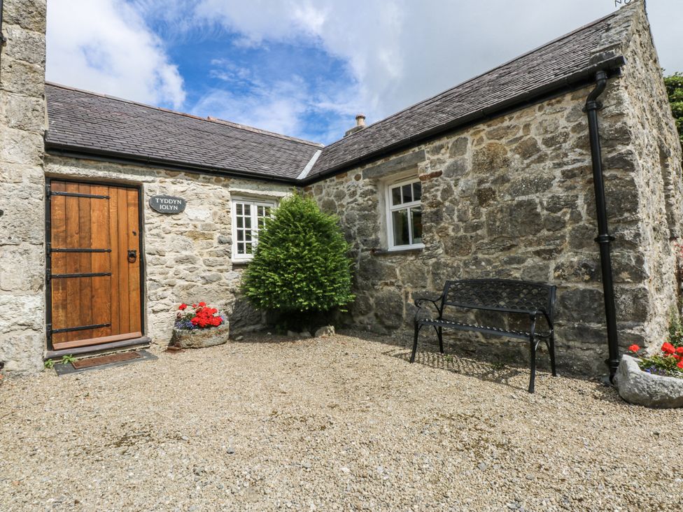 An outdoor area with a bench and a stone building at Tyddyn Iolyn in Benllech