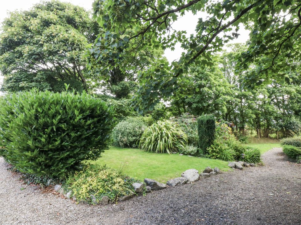 A garden with bushes and a gravel path at Tyddyn Iolyn in Benllech