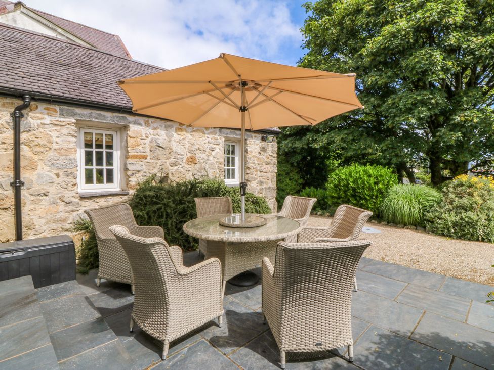 A patio area with a table and chairs at Tyddyn Iolyn in Benllech