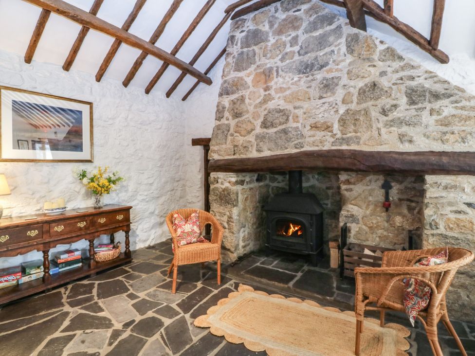 A living room with a stone fireplace and wicker chairs at Tyddyn Iolyn in Benllech