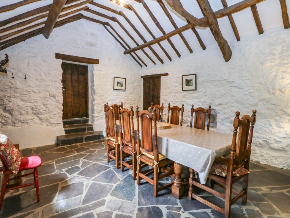 A dining room with wooden furniture and a stone floor at Tyddyn Iolyn Benllech