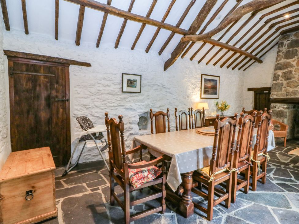 A dining room with a wooden table and chairs at Tyddyn Iolyn in Benllech