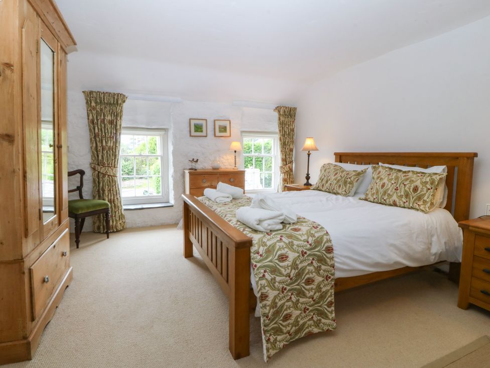 A bedroom with a bed and wardrobe at Tyddyn Iolyn in Benllech