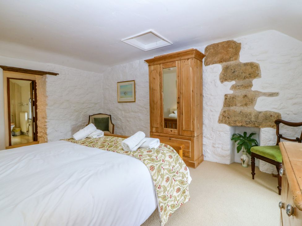 A bedroom with a double bed and wooden wardrobe at Tyddyn Iolyn in Benllech