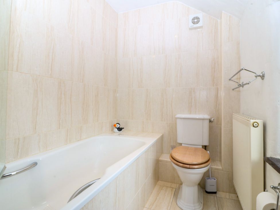 A bathroom with a bathtub and toilet at Tyddyn Iolyn in Benllech