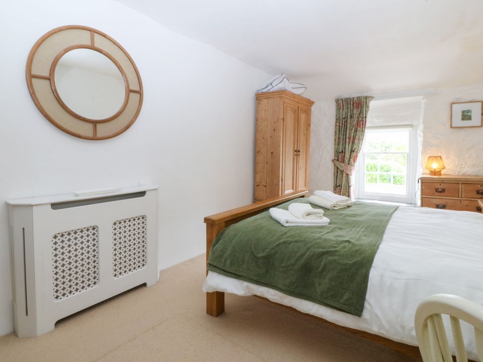 A bedroom with a bed and wardrobe at Tyddyn Iolyn in Benllech