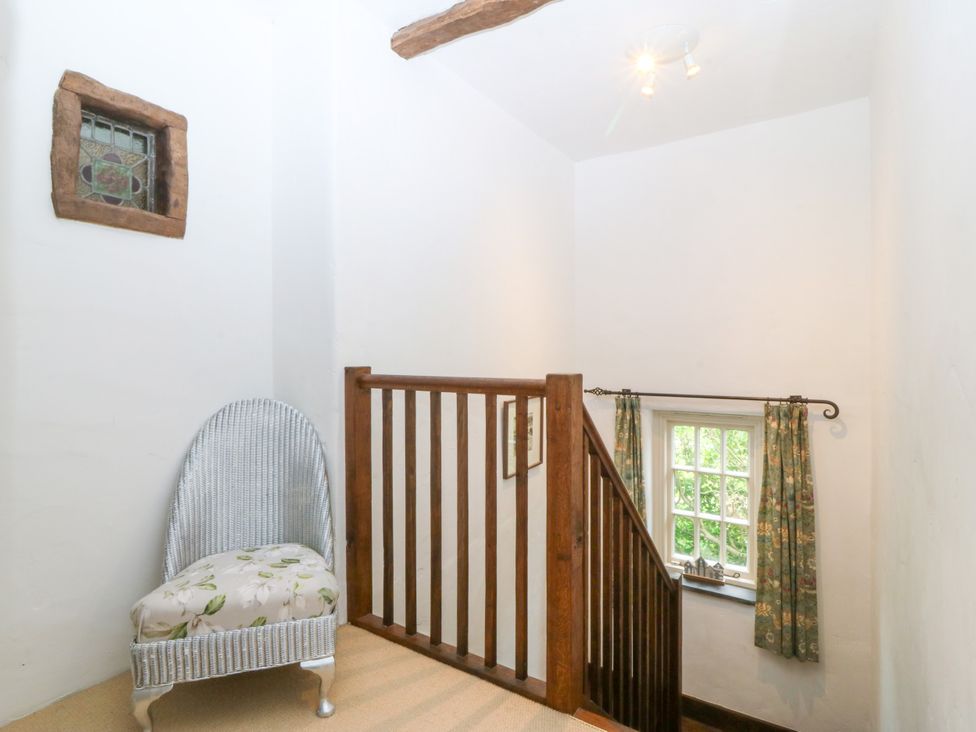 A staircase with a wooden railing and a round chair at Tyddyn Iolyn in Benllech