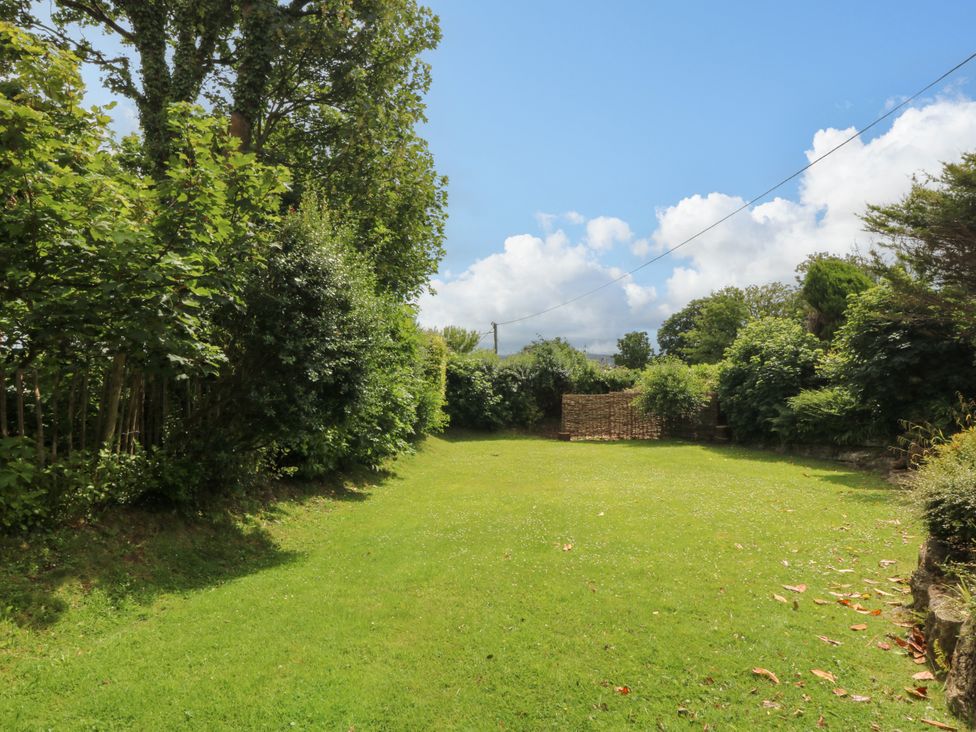 A garden with grass and trees at Tyddyn Iolyn in Benllech