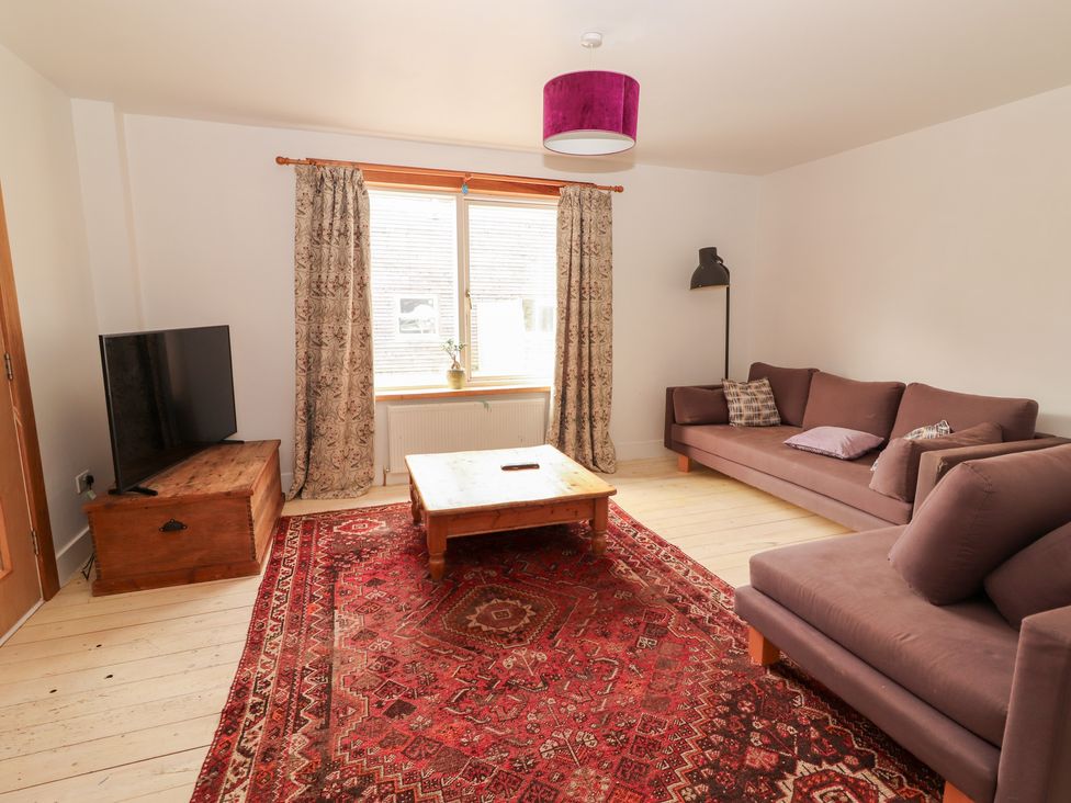 A living room with a sofa, coffee table, and television at Shanti Gher in Bantry