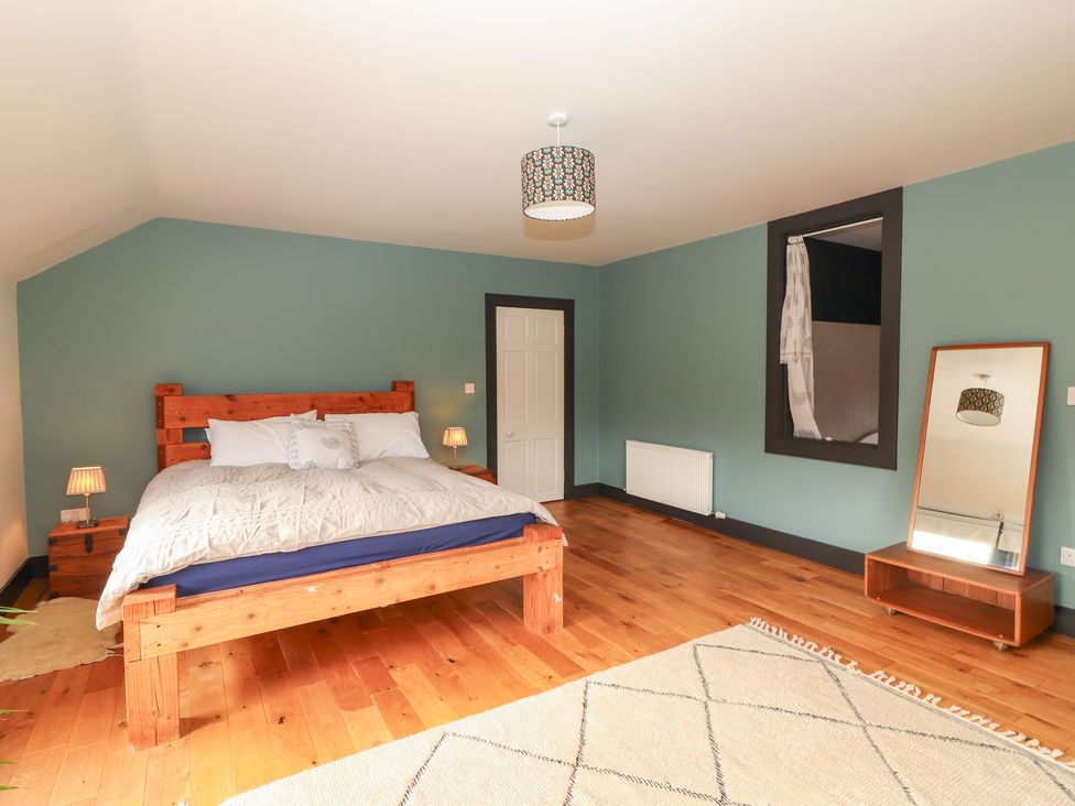 A bedroom with a wooden bed and a mirror at Shanti Gher in Bantry