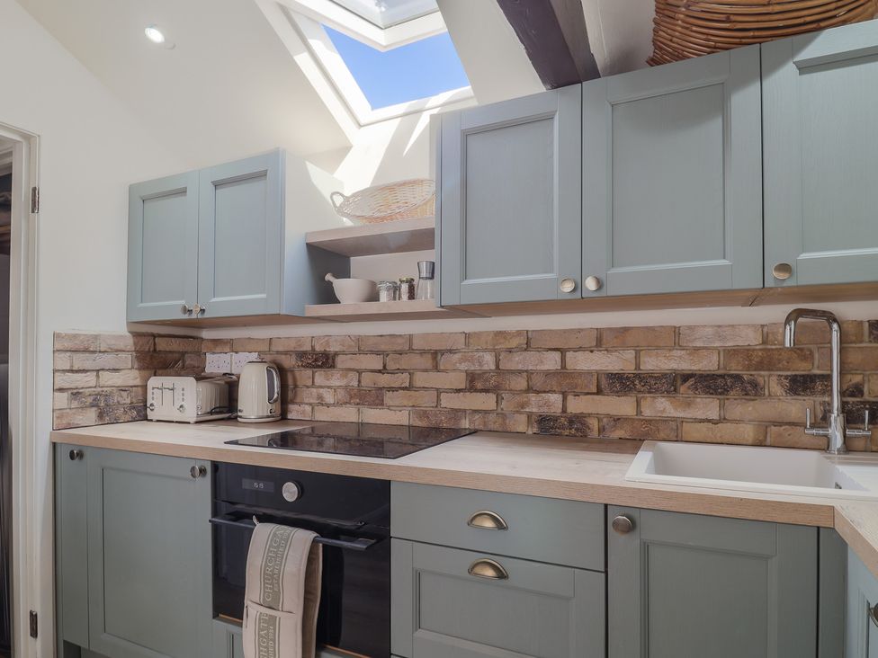 A kitchen with green cabinets a brick backsplash toaster kettle oven and a sink at Drakes Hideaway in Lyme Regis