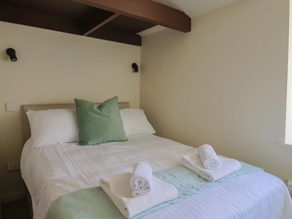 A bedroom with a bed with white linens green pillow and folded towels at Drake's Hideaway in Lyme Regis