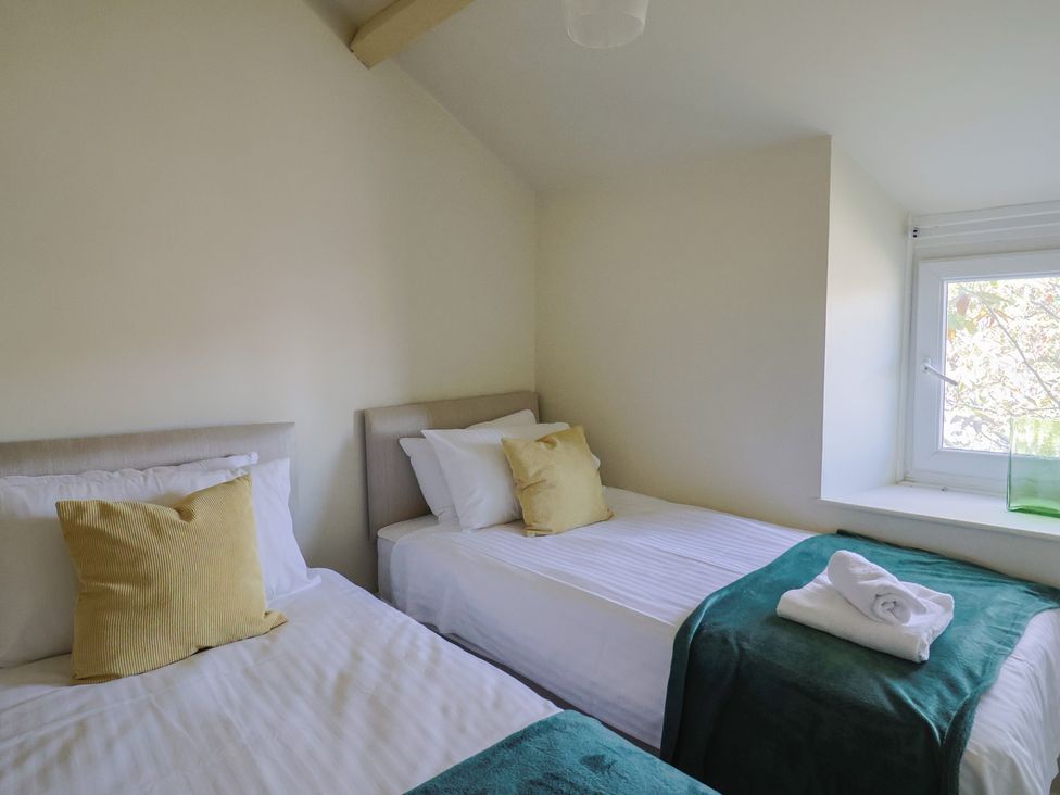 A bedroom with two single beds a window and folded towels on a bed at Drakes Hideaway in Lyme Regis
