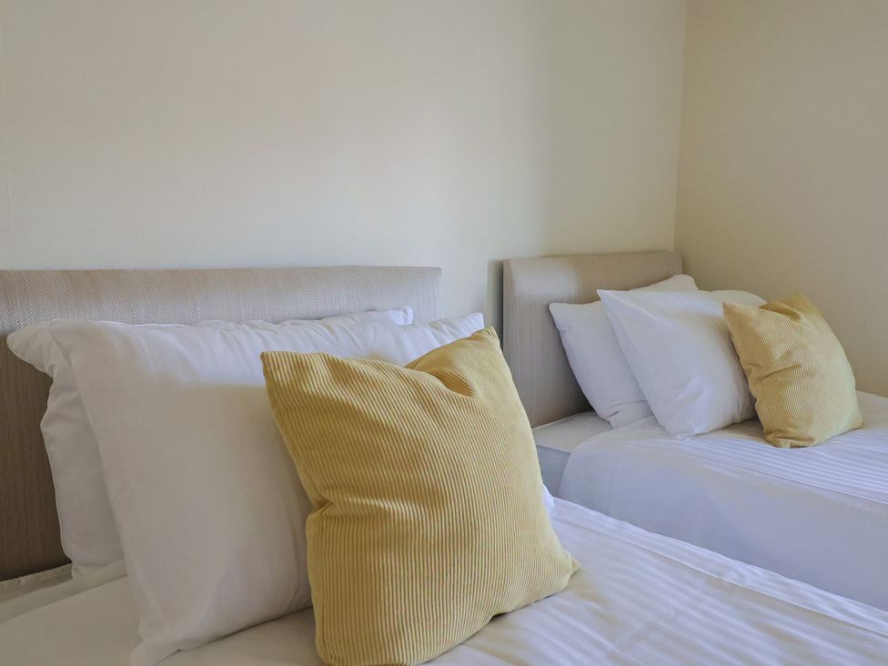 Two beds with white pillows and yellow cushions in a bedroom at Drakes Hideaway in Lyme Regis