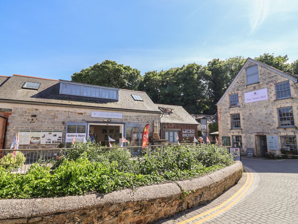 Stone buildings including The Town Mill and a microbrewery with plants and a curved stone wall in front at Drake's Hideaway in Lyme Regis