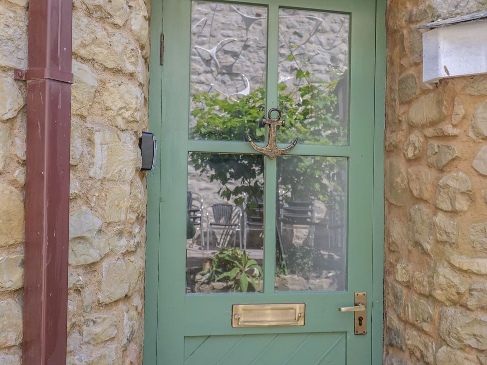 A green door with an anchor decoration at Drake's Hideaway in Lyme Regis