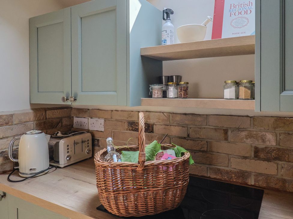 A kitchen with cabinets, kettle, toaster, and a basket at Drake's Hideaway in Lyme Regis