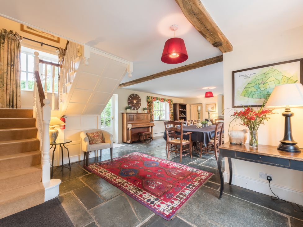 A dining room with a staircase and piano at The Coach House Lydford