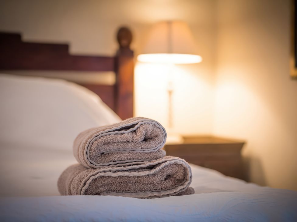 A bed with rolled towels and a lamp at The Coach House in Lydford