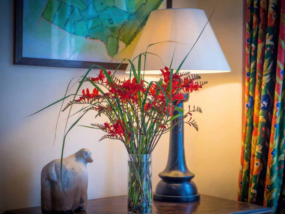 A vase with flowers and a lamp on a table at The Coach House in Lydford