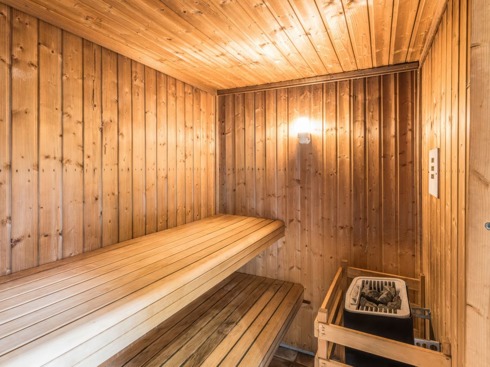 A sauna with wooden benches and a heater at The Coach House Lydford