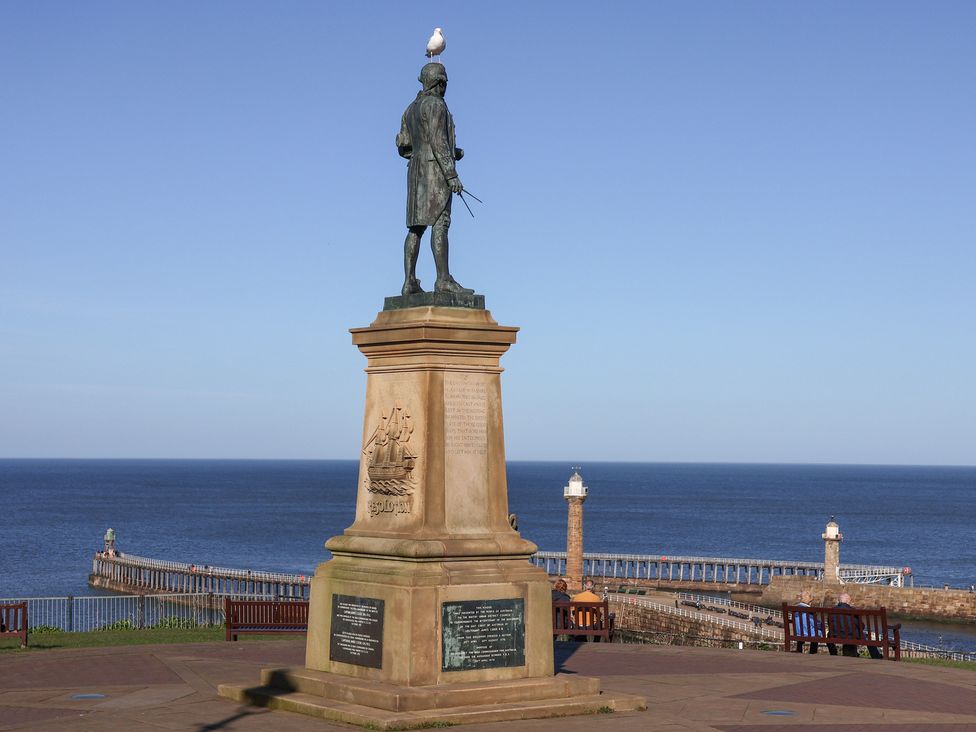 A statue near the ocean and pier at Pebble Cottage in Whitby