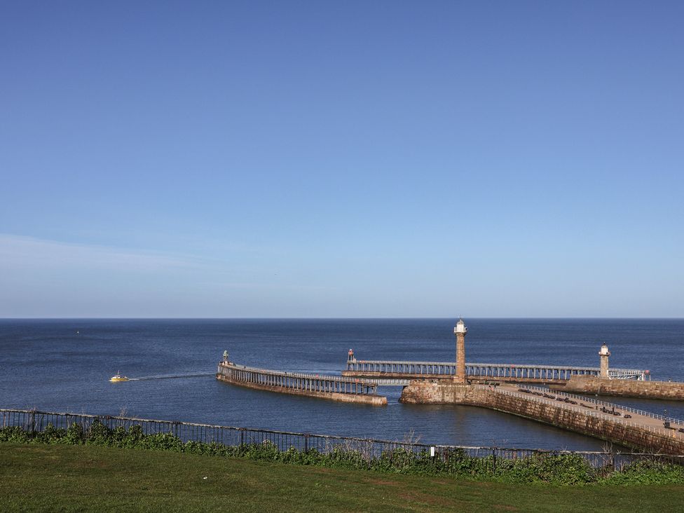 View of a pier and lighthouse over the sea at Pebble Cottage in Whitby