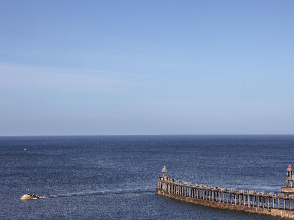 A pier extending into the sea with a yellow boat at Pebble Cottage in Whitby