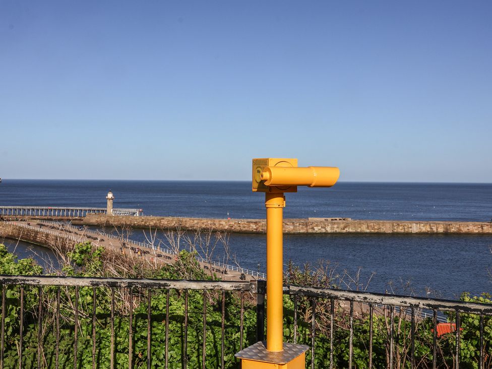 A telescope overlooking the ocean and pier at Pebble Cottage in Whitby