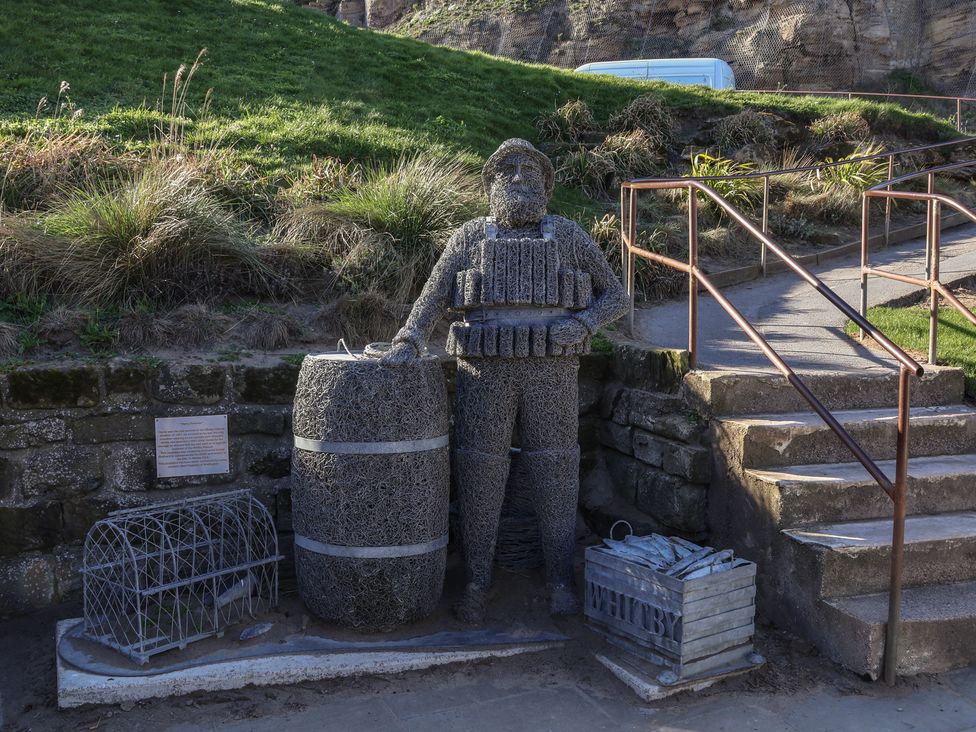 A sculpture of a fisherman with a barrel and fishing trap at Pebble Cottage in Whitby